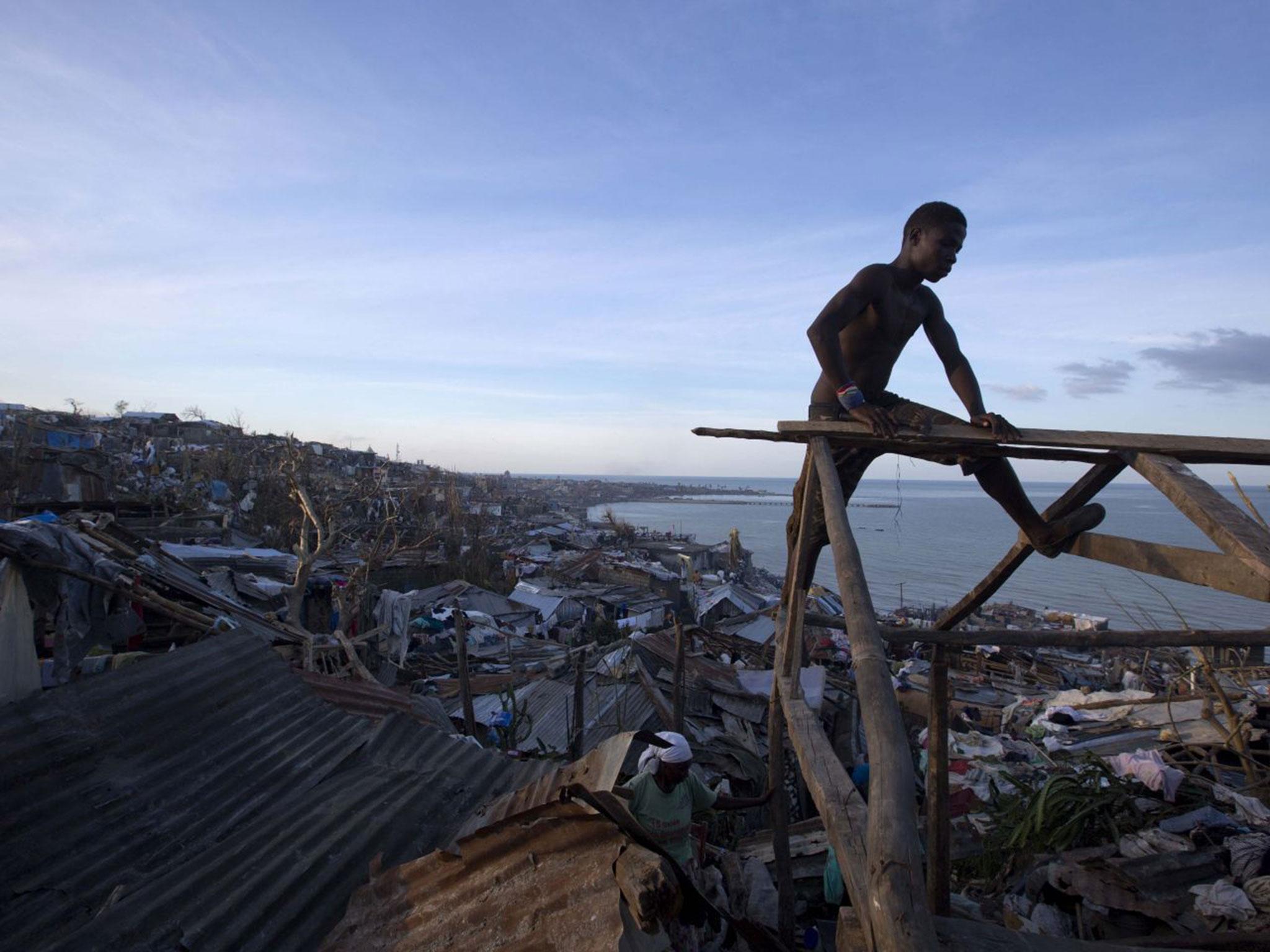 A man works to repair his roof after hurricane damage in Jeremie, Haiti