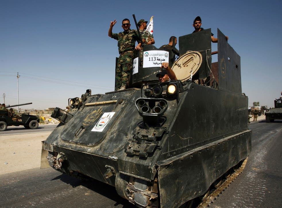 Iraqi soldiers supporting the government driving an armoured tank in Najaf as part of military parage to review equipment for the planned assault on Mosul