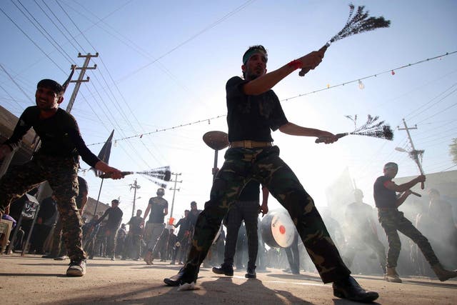 Iraqi Shiite men beat themselves with chains during a parade in preparation for the peak of the mourning period of Ashura on October 9, 2016 in the southern city of Basra