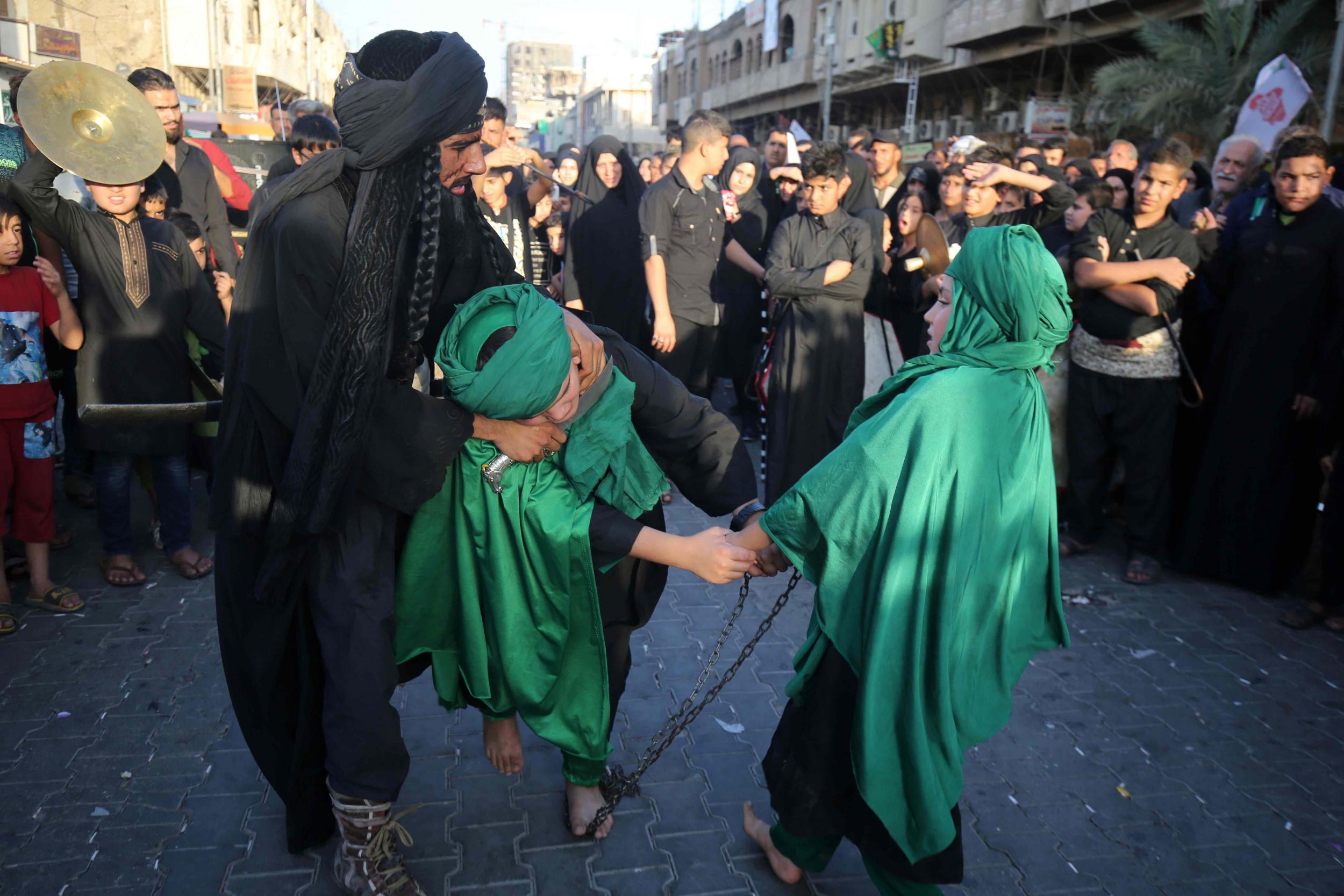 Iraqi Shiite children and a man perform during the reenactment of the Battle of Karbala, as part of a parade in preparation for the peak of the mourning period of Ashura on October 7, 2016 in Baghdad's northern district of Kadhimiya