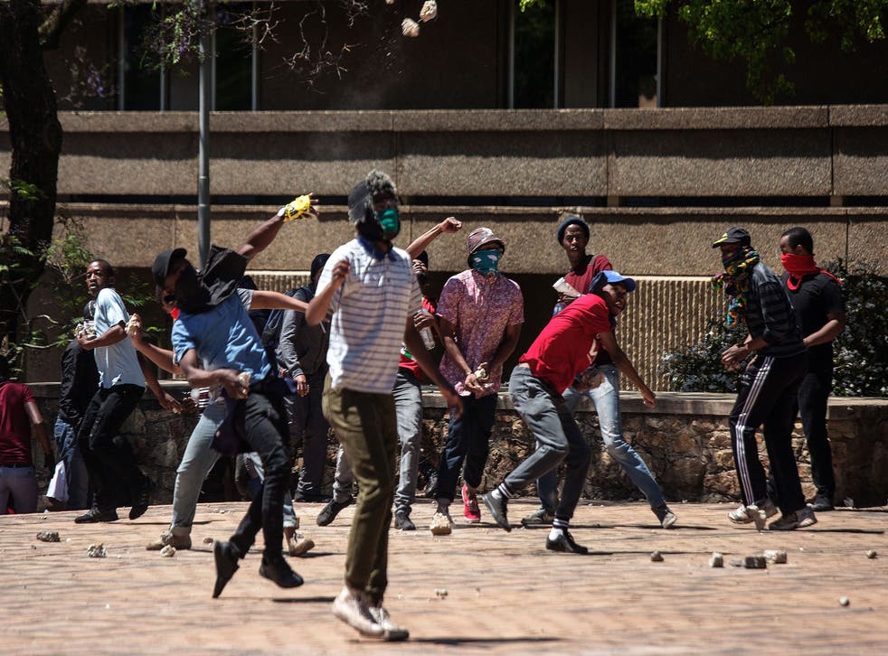 Students from the University of Witwatersrand hurl stones at private security guards during a protest on Tuesday