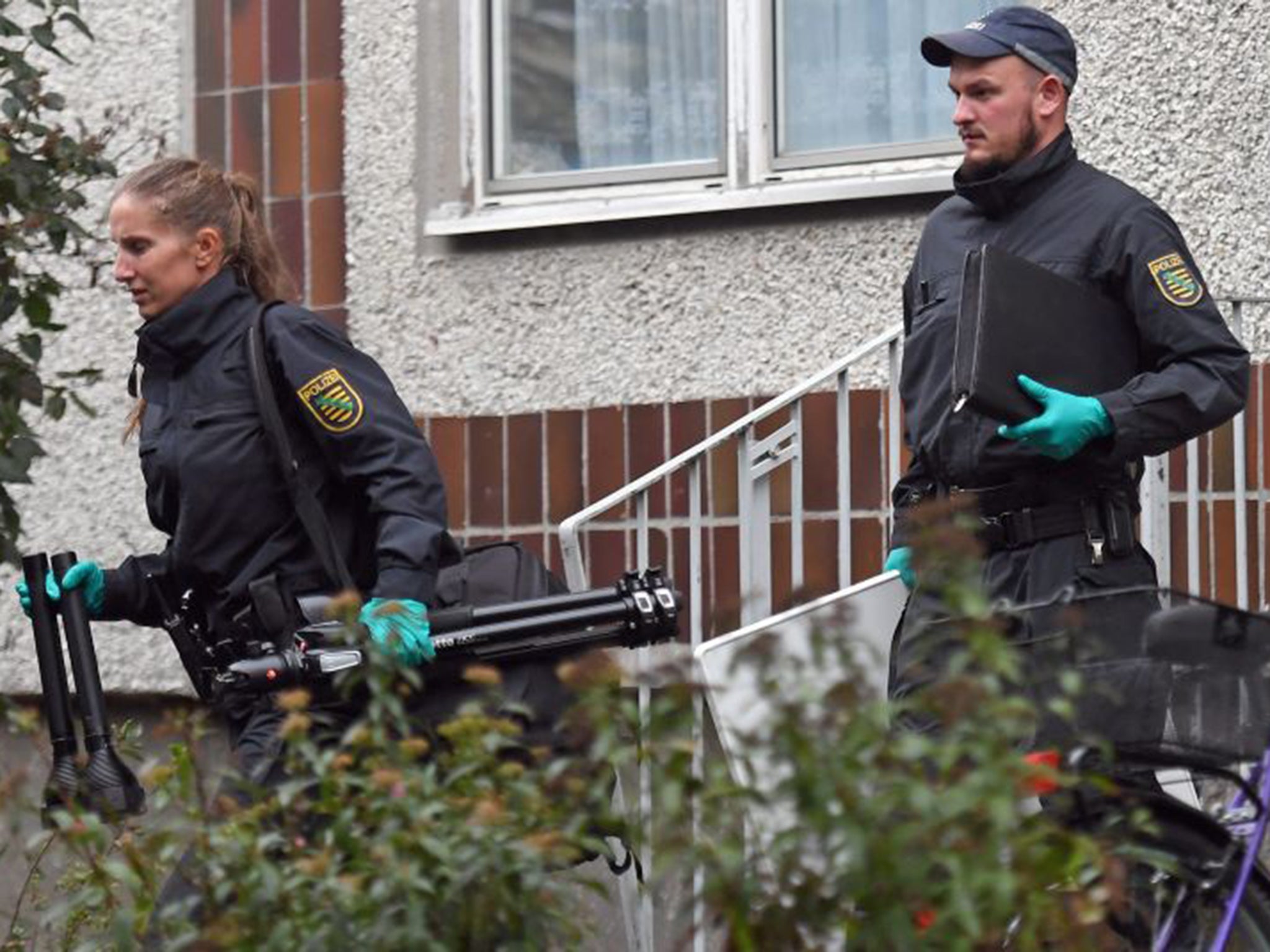 German police and crime scene investigators exit an appartment complex in the Pausdorf district of Leipzig