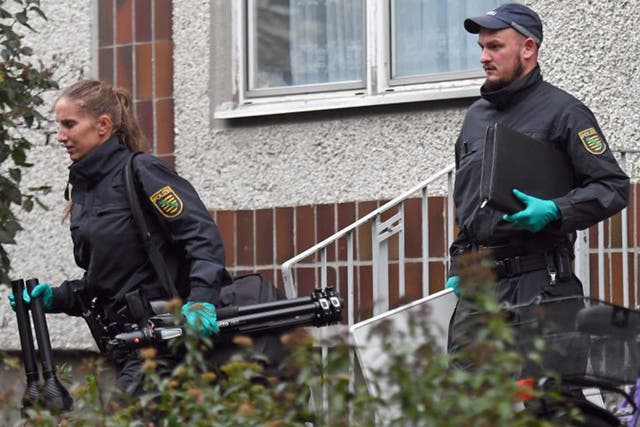 German police and crime scene investigators exit an appartment complex in the Pausdorf district of Leipzig