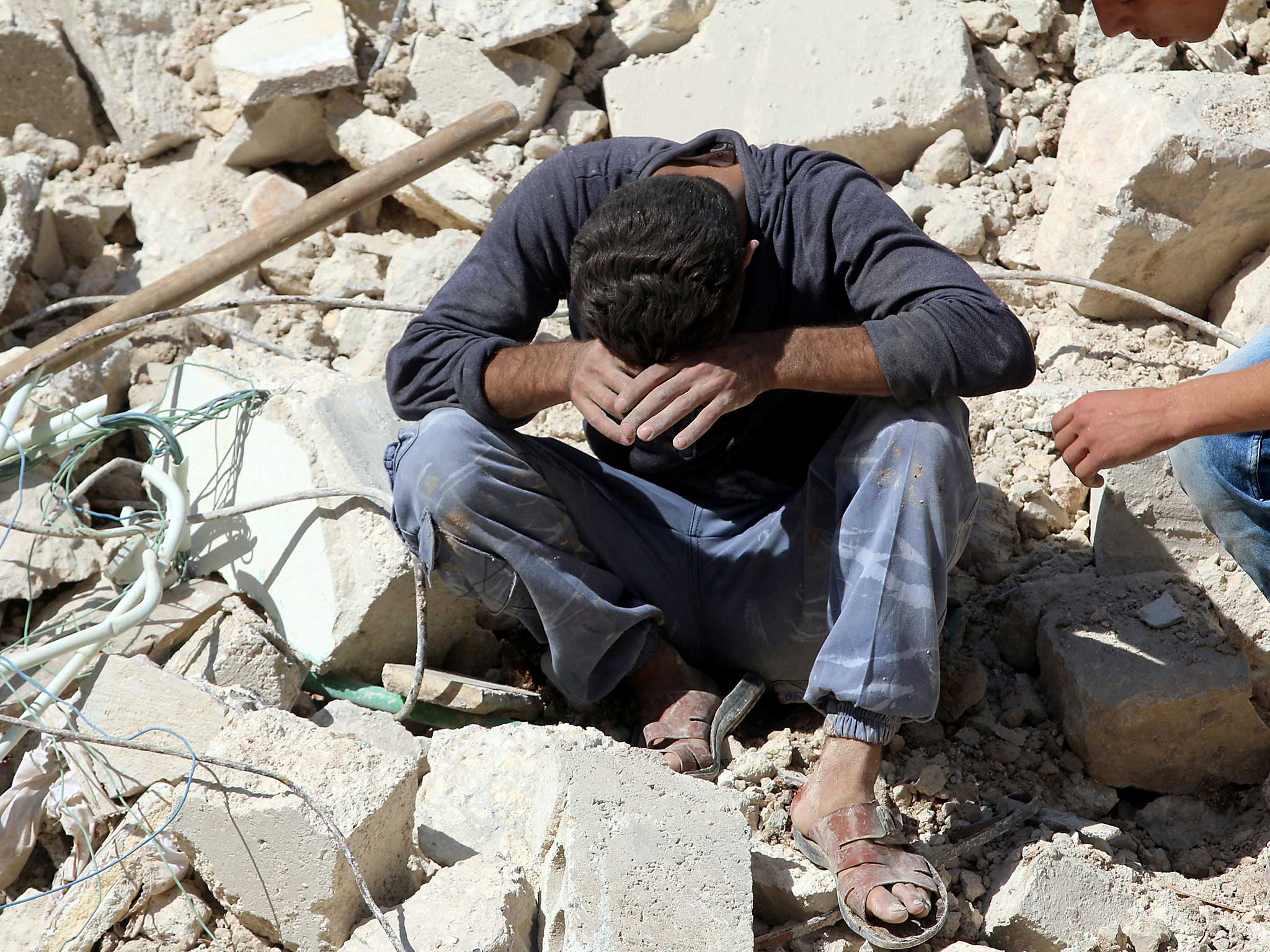 A man breaks down in tears on the rubble of damaged buildings after losing relatives to an airstrike in the besieged rebel-held al-Qaterji neighbourhood of Aleppo, Syria