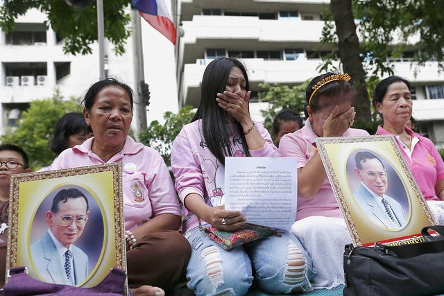 Thai well-wishers hold portraits of Thai King Bhumibol Adulyadej as they pray and wish for a healthy recovery for the king at Siriraj Hospital in Bangkok, Thailand