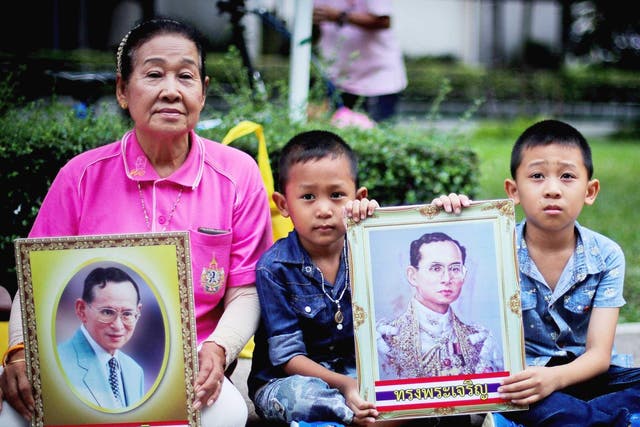 Thai well-wishers pray with portraits of Thai King Bhumibol Adulyadej, wishing for the King's recovery, outside the Siriraj Hospital in Bangkok, Thailand