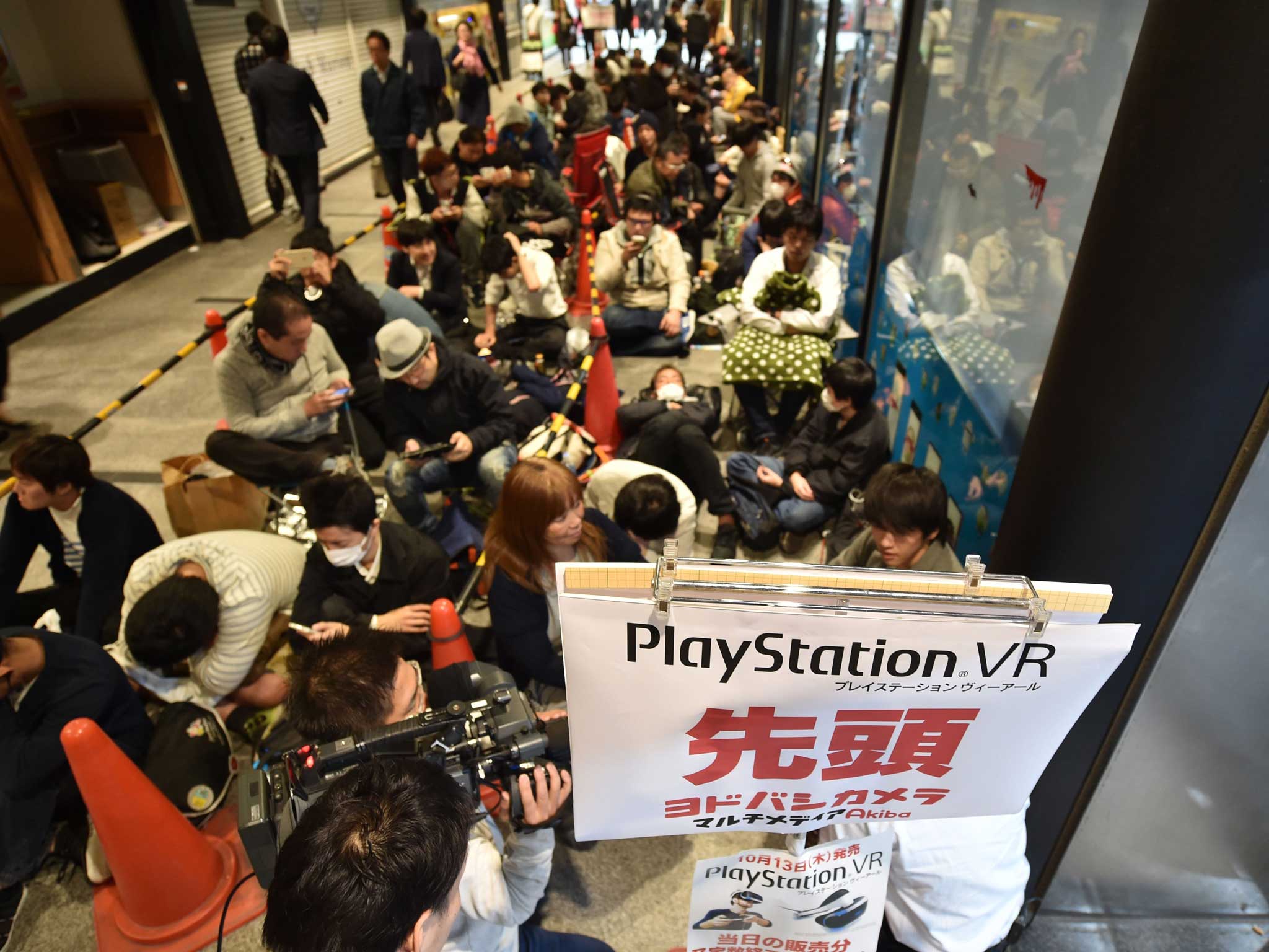 Customers wait in line to buy the Sony PlayStation virtual reality (PSVR) headset at the entrance of an electronics retail shop before its opening hours in Tokyo