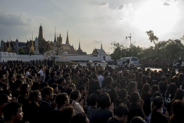 Thousands gather to watch a motorcade carry the body of King Bhumibol Adulyadej into the Grand Palace in Bangkok
