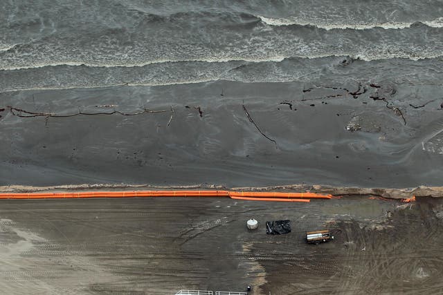 Oily absorbent material and containment booms are placed on the beach in efforts to clean up the oil spill