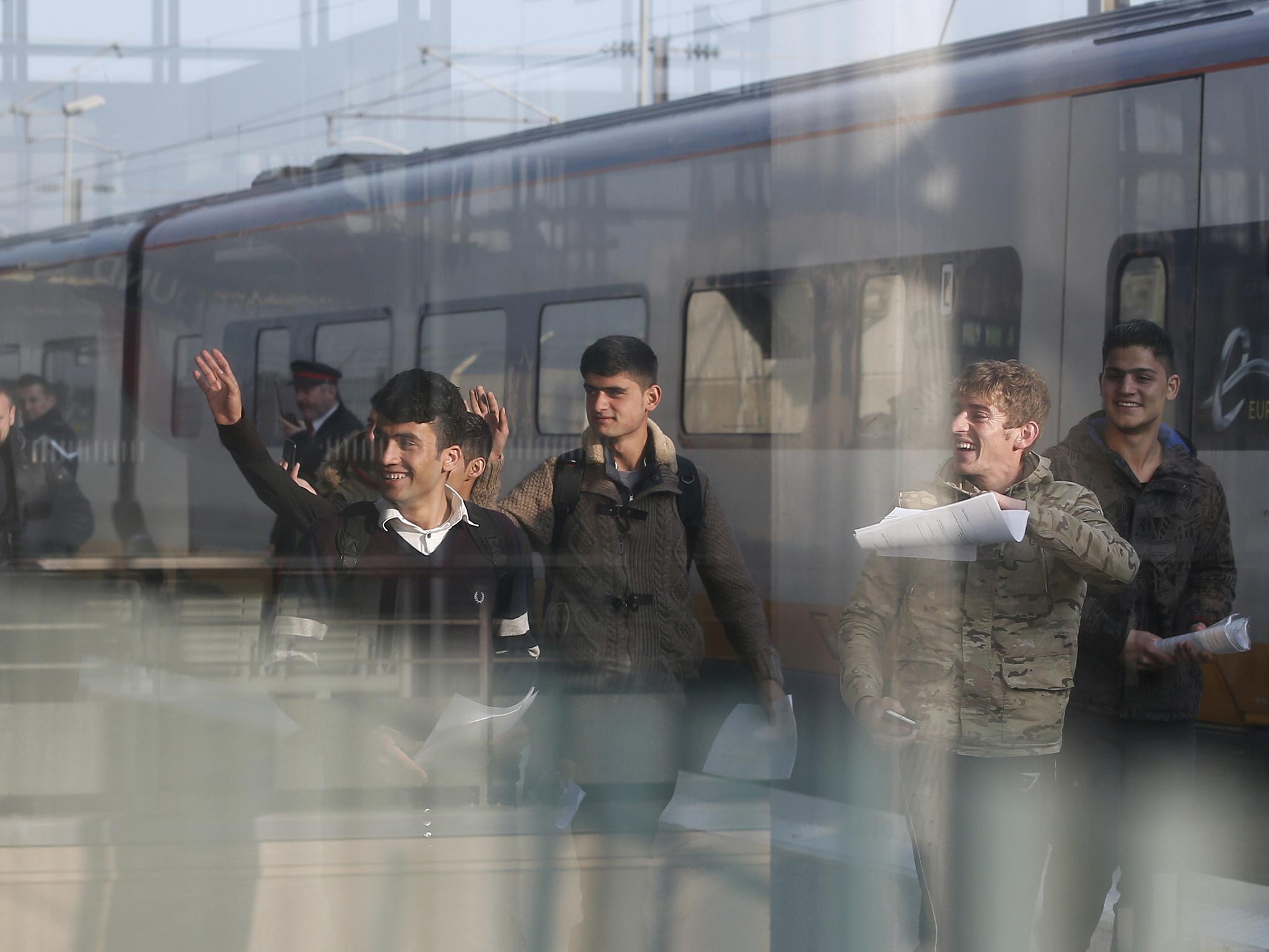 One Syrian and five Afghan boys wave on the platform of the Calais train station, northern France, as they leave for Britain on Thursday