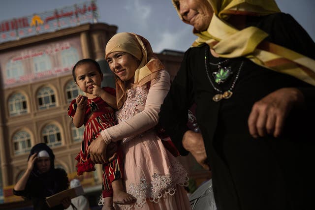 A Uighur woman walks with her baby at a market on August 1, 2014 in old Kashgar, Xinjiang Province, China.
