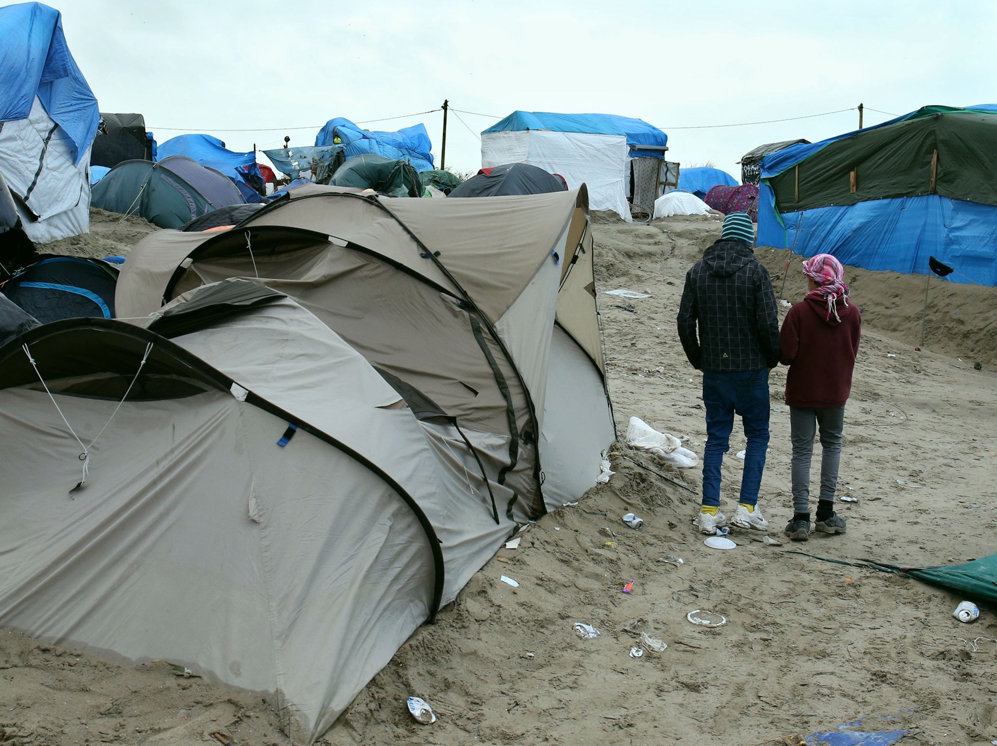 Orphaned refugee children walking amongst the shelters at the Jungle camp at Calais in France