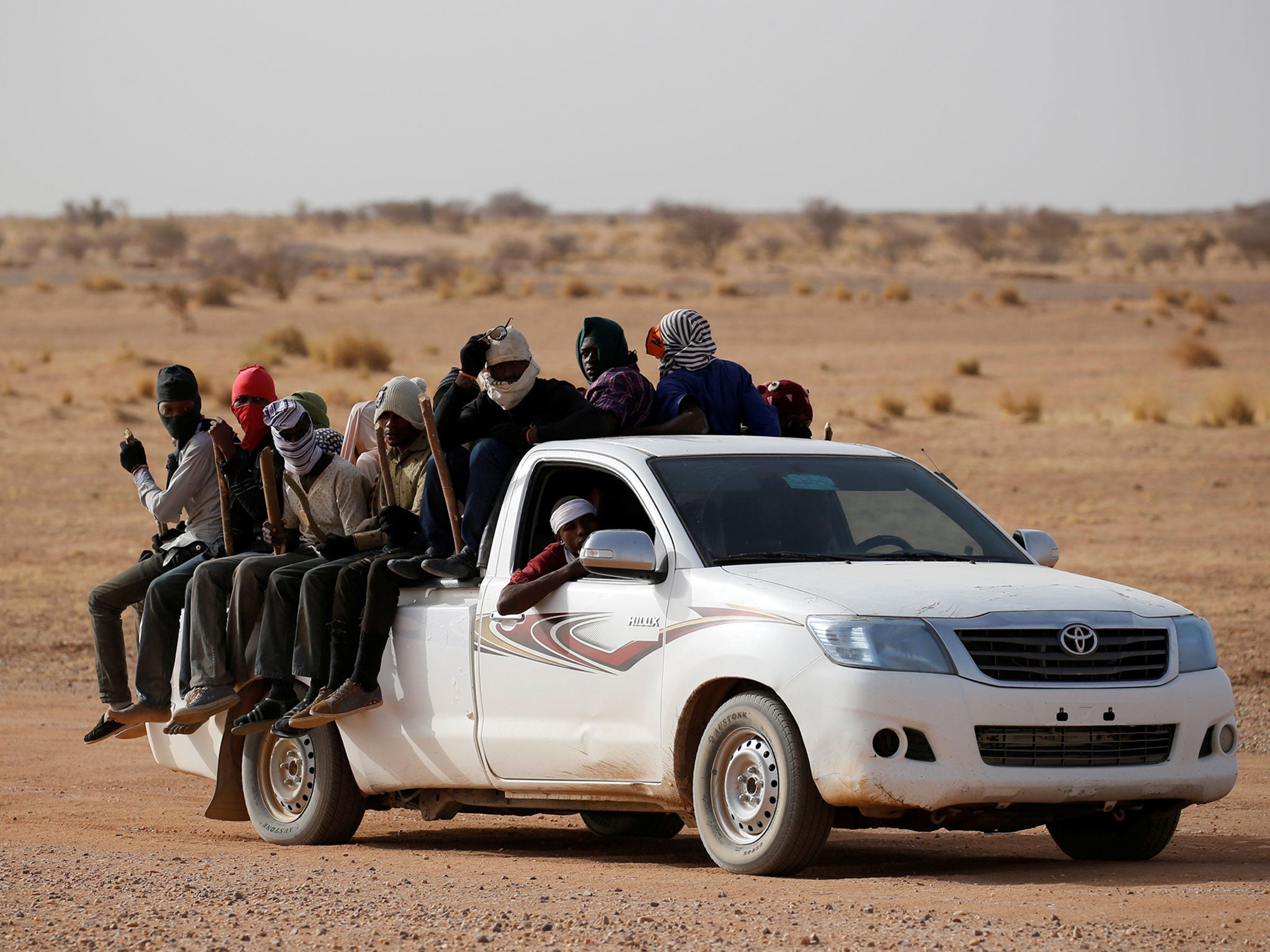 Migrants crossing the Sahara desert into Libya ride on the back of a pickup truck outside Agadez, Niger, May 9, 2016