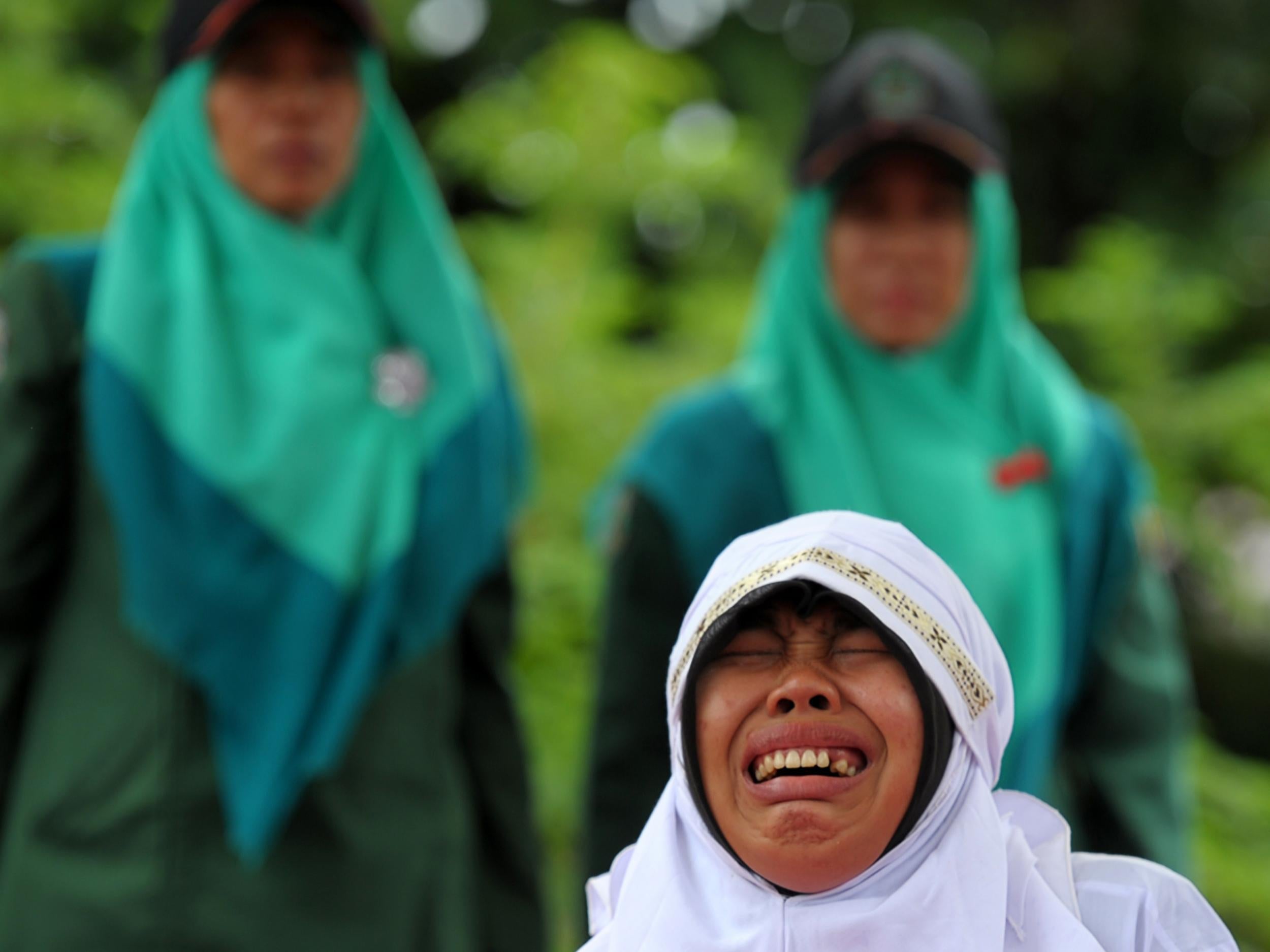 A woman cries as she is hit 23 times with a cane for spending time with her boyfriend in Banda Aceh, Indonesia