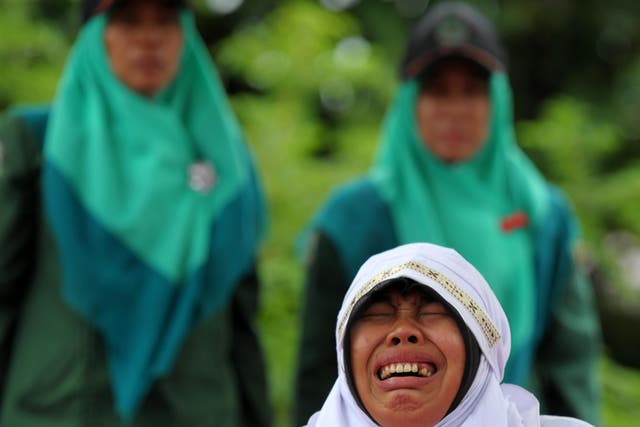 A woman cries as she is hit 23 times with a cane for spending time with her boyfriend in Banda Aceh, Indonesia