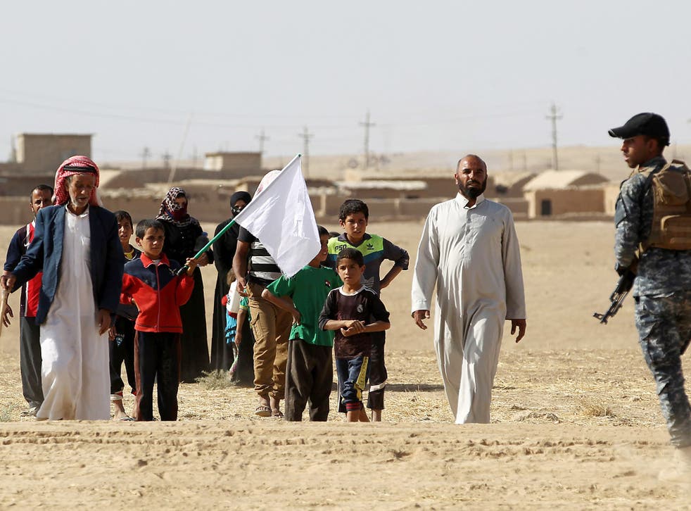 Displaced Iraqis from the Bajwaniyah village, about 30 kms south of Mosul, who fled fighting in the Mosul area carry a white flag as they approach security forces