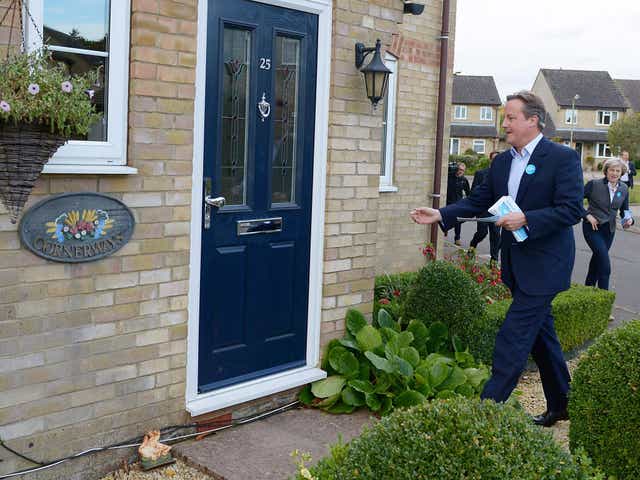 Former Prime Minister David Cameron (L) and British Prime Minister Theresa May (R) post fliers through doors with  Robert Courts, the Conservative candidate for the Witney by-election
