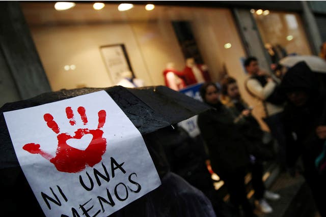 A woman carries a sign that reads "Not another (woman) less" on her umbrella during a demonstration in Buenos Aires