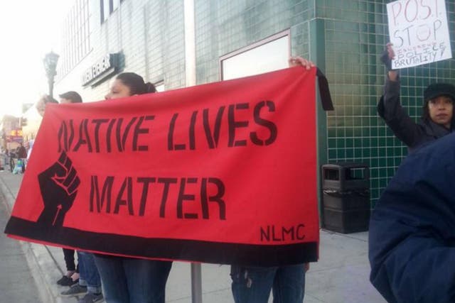 A woman holds up a 'Native Lives Matter' banner, a movement which started in late 2014