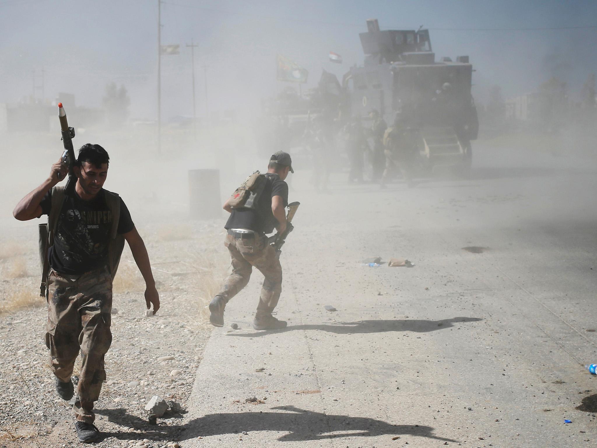 Iraqi special forces soldiers run for cover during clashes with Isis fighters in Bartella, east of Mosul