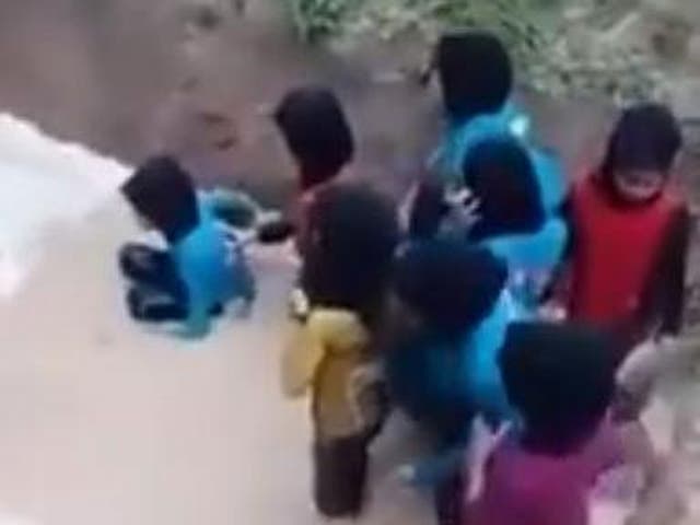 Malaysian school girls huddle in a muddy put, avoiding a snake