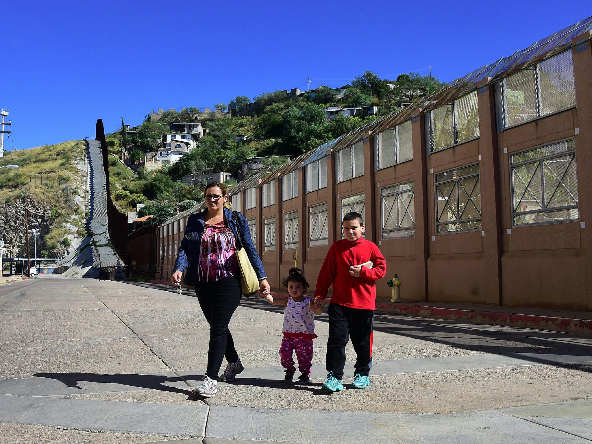 A woman and two children on the Nogales side of the border in Arizona leave after speaking with people across the border wall on the Mexico side in the state of Sonora on October 11, 2016