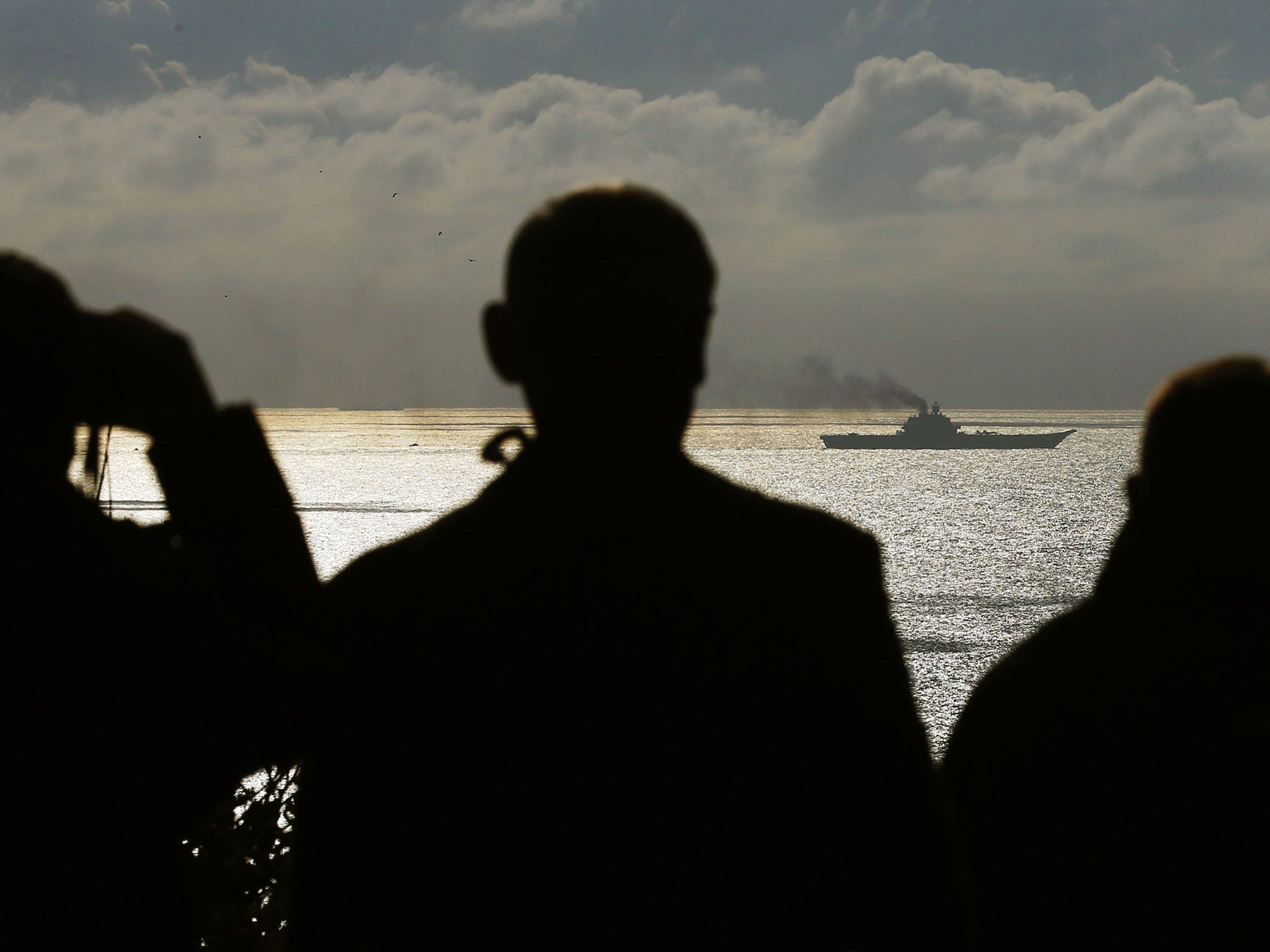 People watch as the Russian aircraft carrier Admiral Kuznetsov passes through the Strait of Dover on 21 October 2016