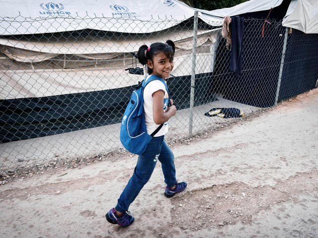 Roza, a Syrian Kurd refugee, walks through a camp to reach a volunteer-run school 