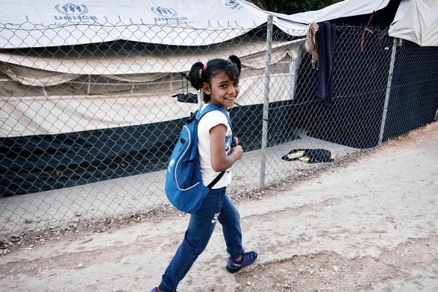 Roza, a Syrian Kurd refugee, walks through a camp to reach a volunteer-run school 