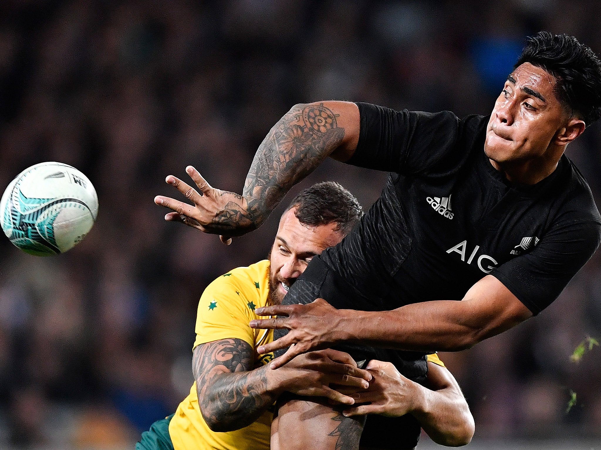 Malakai Fekitoa offloads the ball as Quade Cooper attempts to stop him