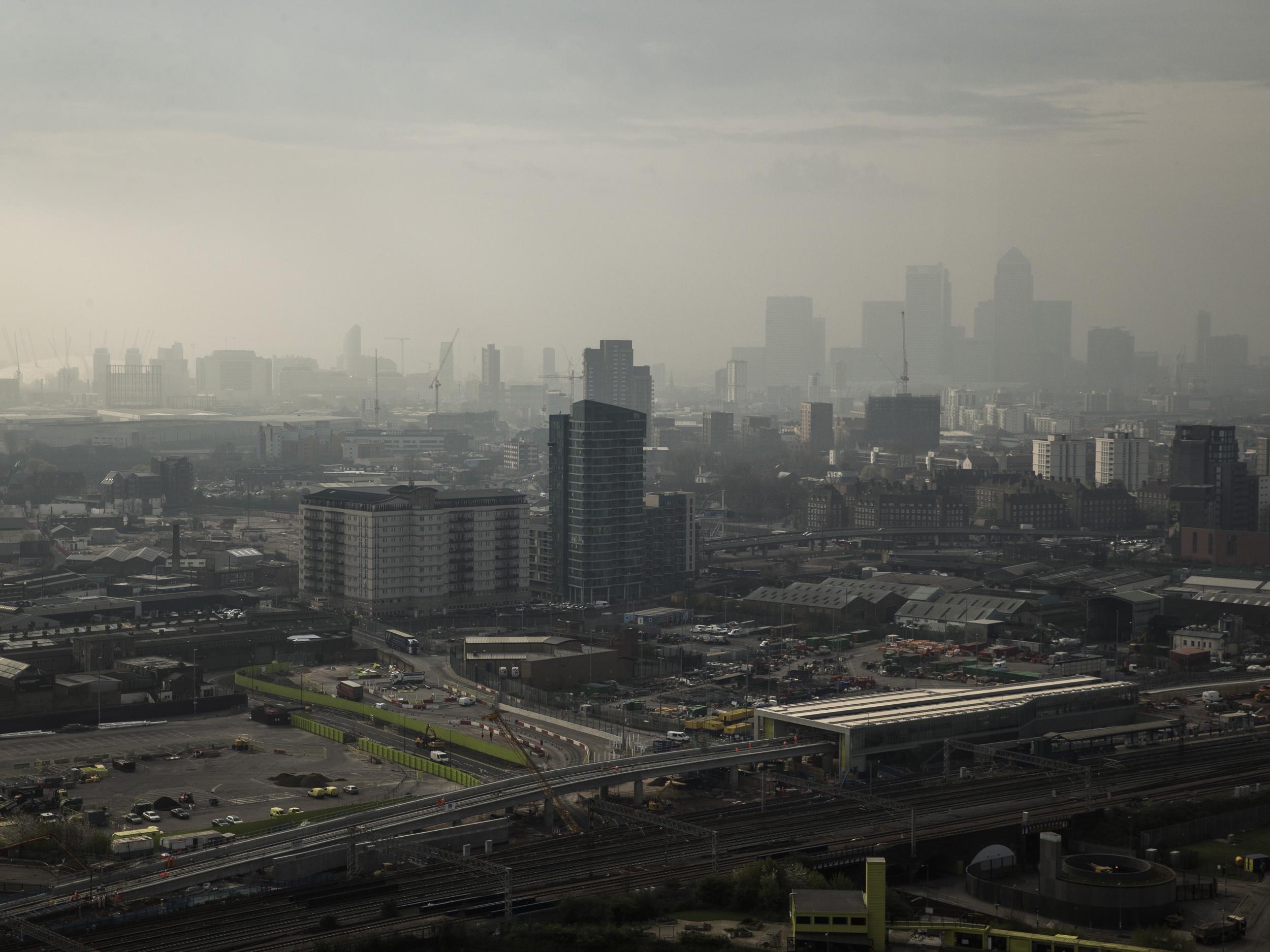 A general view through smog over the 02 Arena and the Canary Wharf financial district in London, England