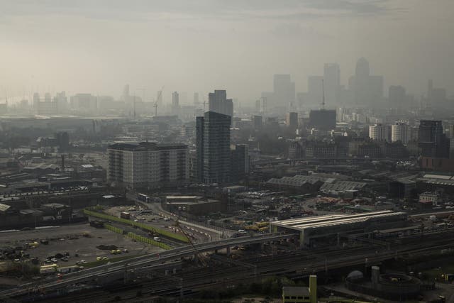 A general view through smog over the 02 Arena and the Canary Wharf financial district in London, England