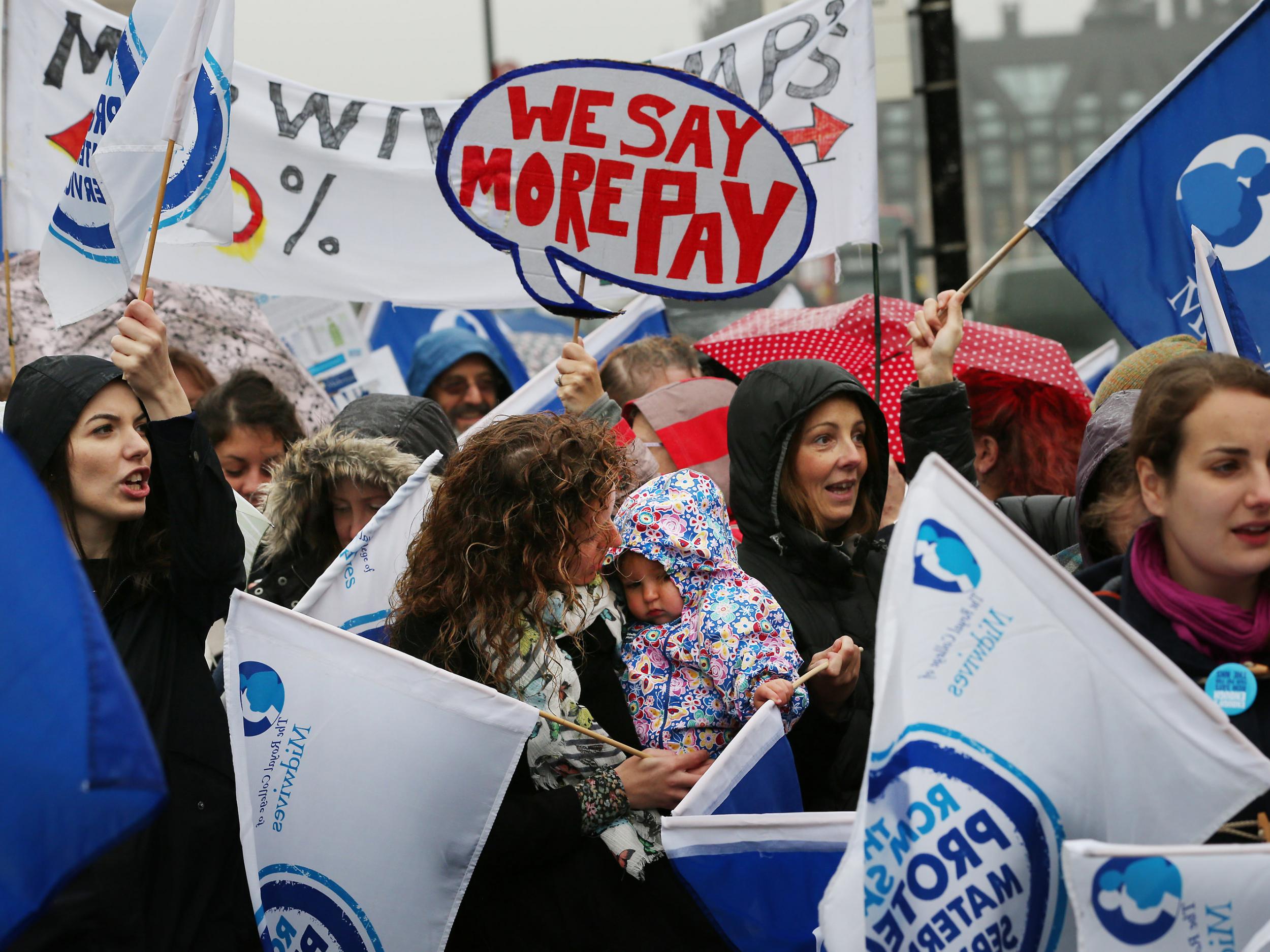 NHS workers, including a midwife and her baby (centre), gather outside a hospital in London, during a four hour strike over pay