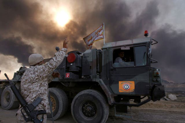 Iraqi army are seen in Qayyarah, Iraq, October 22, 2016. The fumes in the background are from oil wells that were set ablaze by Islamic State militants.
