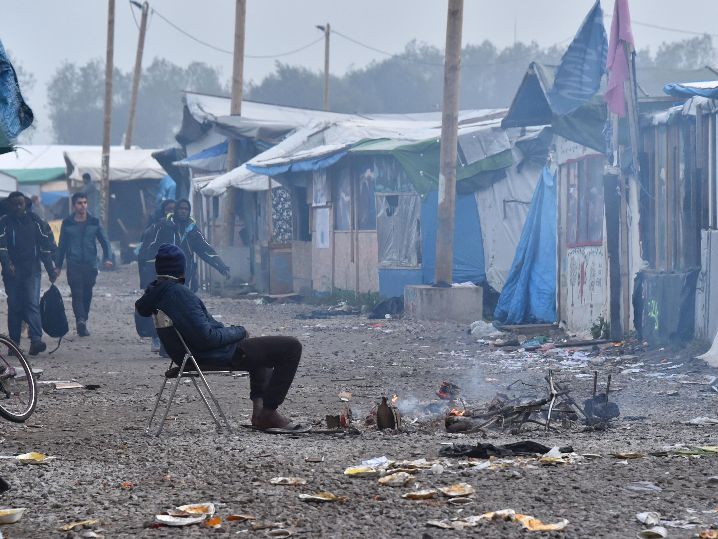 People carrying suitcases walk to an official meeting point set by French authorities as part of the full evacuation of the Calais 'Jungle' camp (Getty Images )