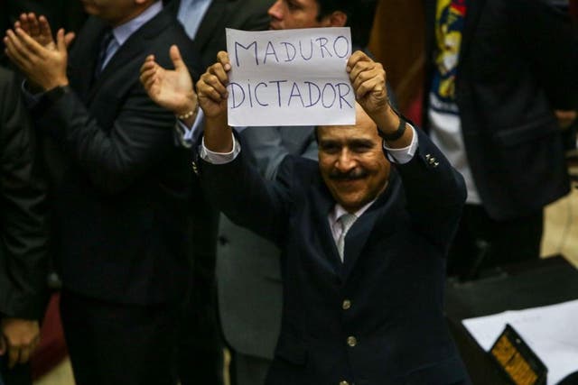 Opposition deputy Luis Silva holds a banner against Venezuelan President Nicolas Maduro, that says "Maduro dictator" during the debate in the National Assembly in Caracas, Venezuela, on 23 October, 2016