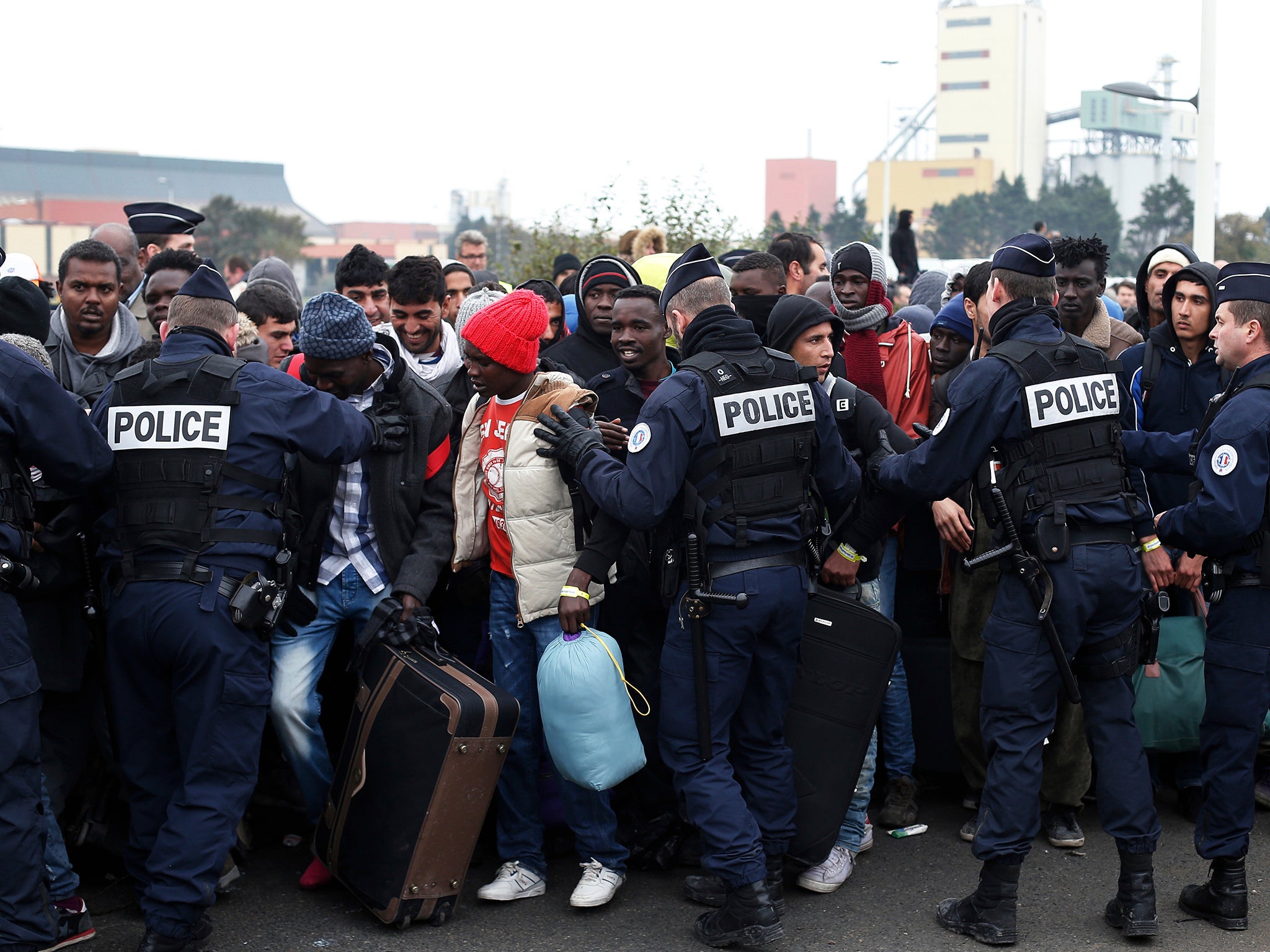 Riot police push back people lining up to register at a processing center in the makeshift migrant camp known as "the Jungle"