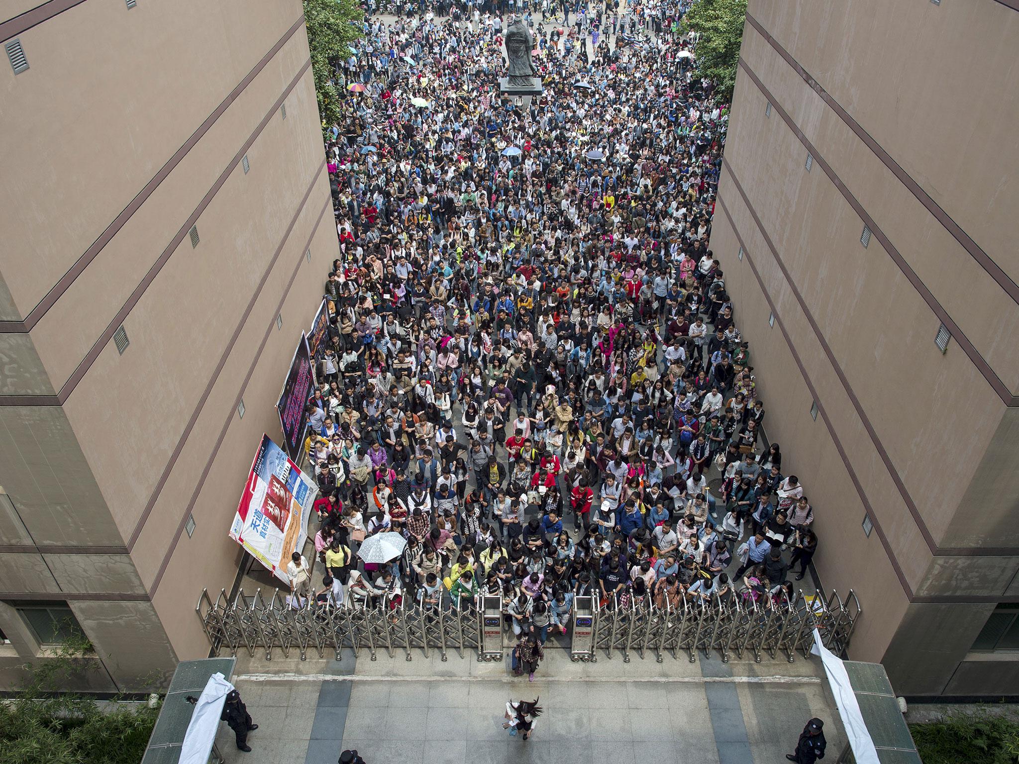 Applicants queue up to enter an entrance to a university to take part in a civil service entrance exam