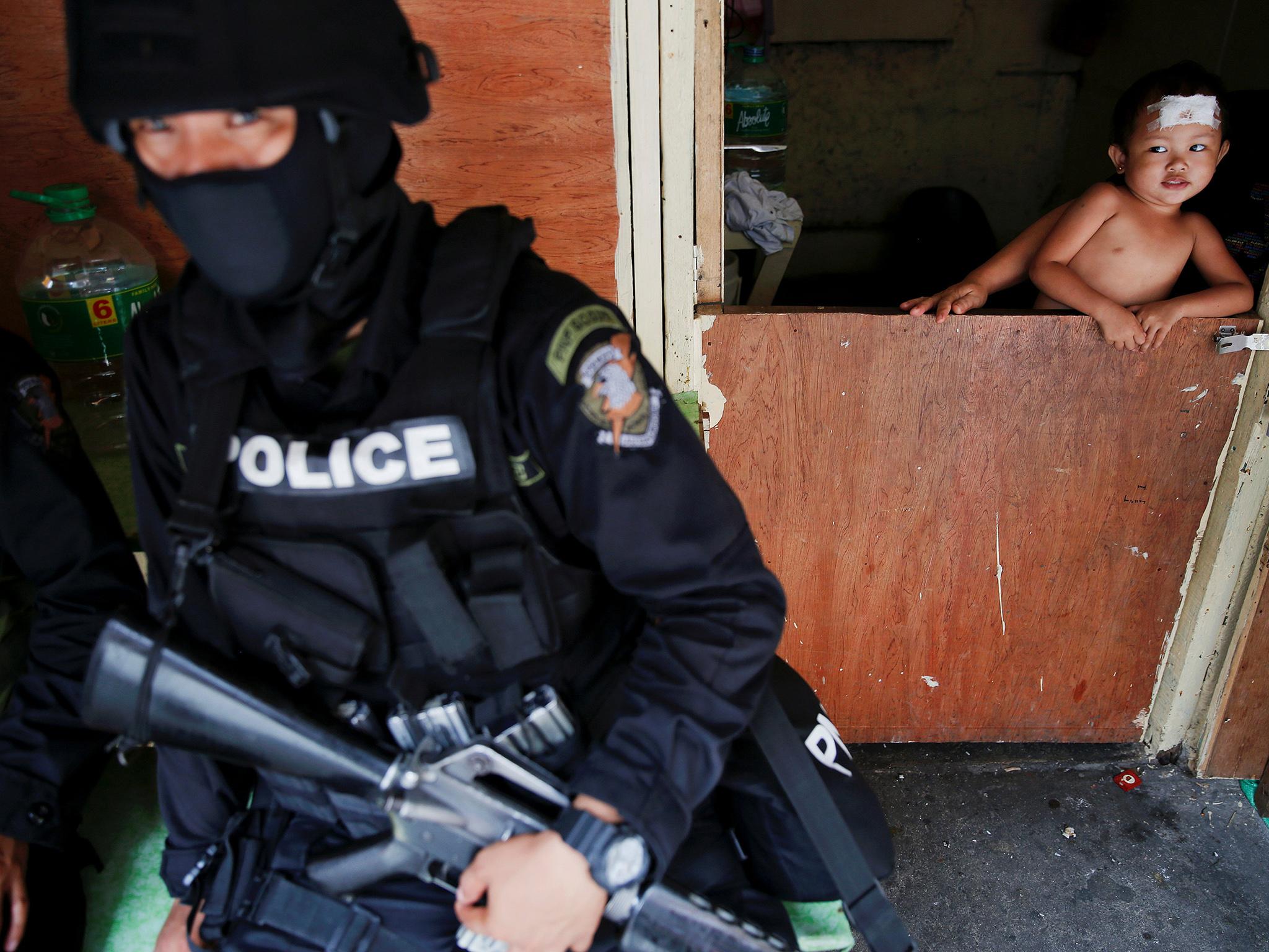 A baby looks at a member of a police SWAT team during a drug raid in Manila