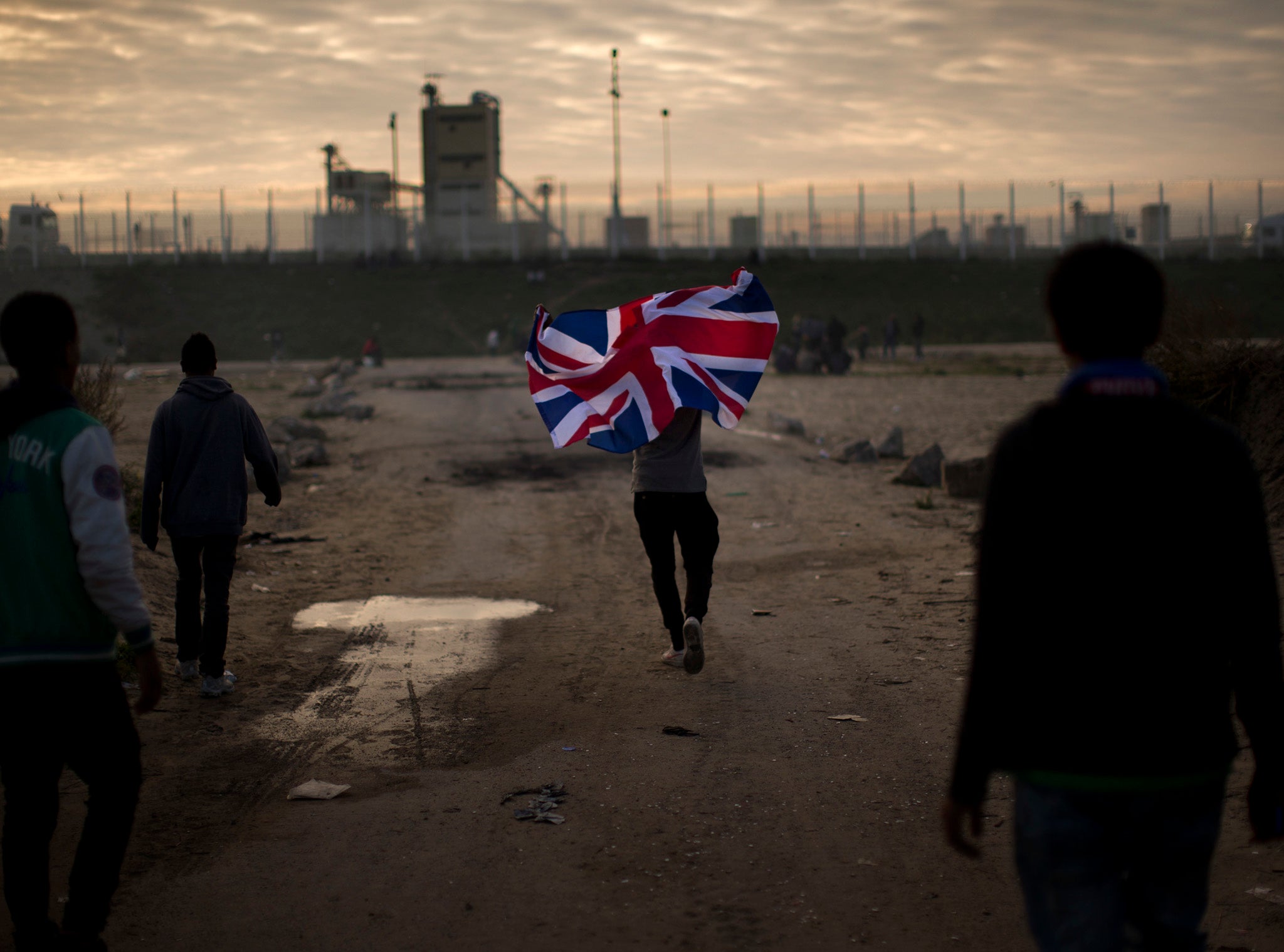 A man runs with a British flag during the mass evacuation of the Calais 'Jungle'