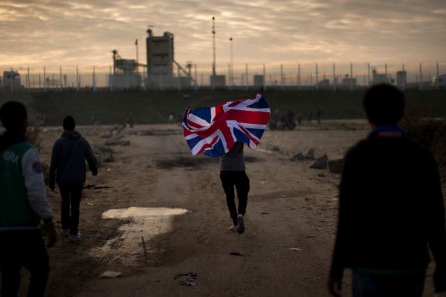 A man runs with a British flag during the mass evacuation of the Calais 'Jungle'
