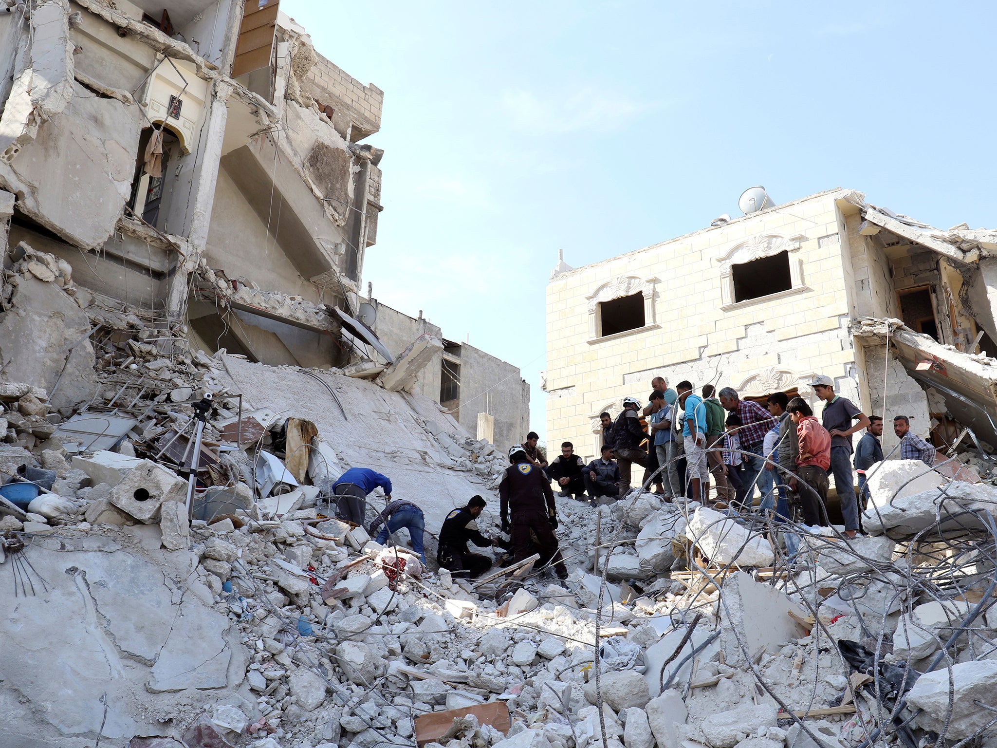 Civil defense members and civilians search for survivors under the rubble of a site hit by overnight airstrikes in the town of Kafr Takharim, in Idlib Governorate, Syria