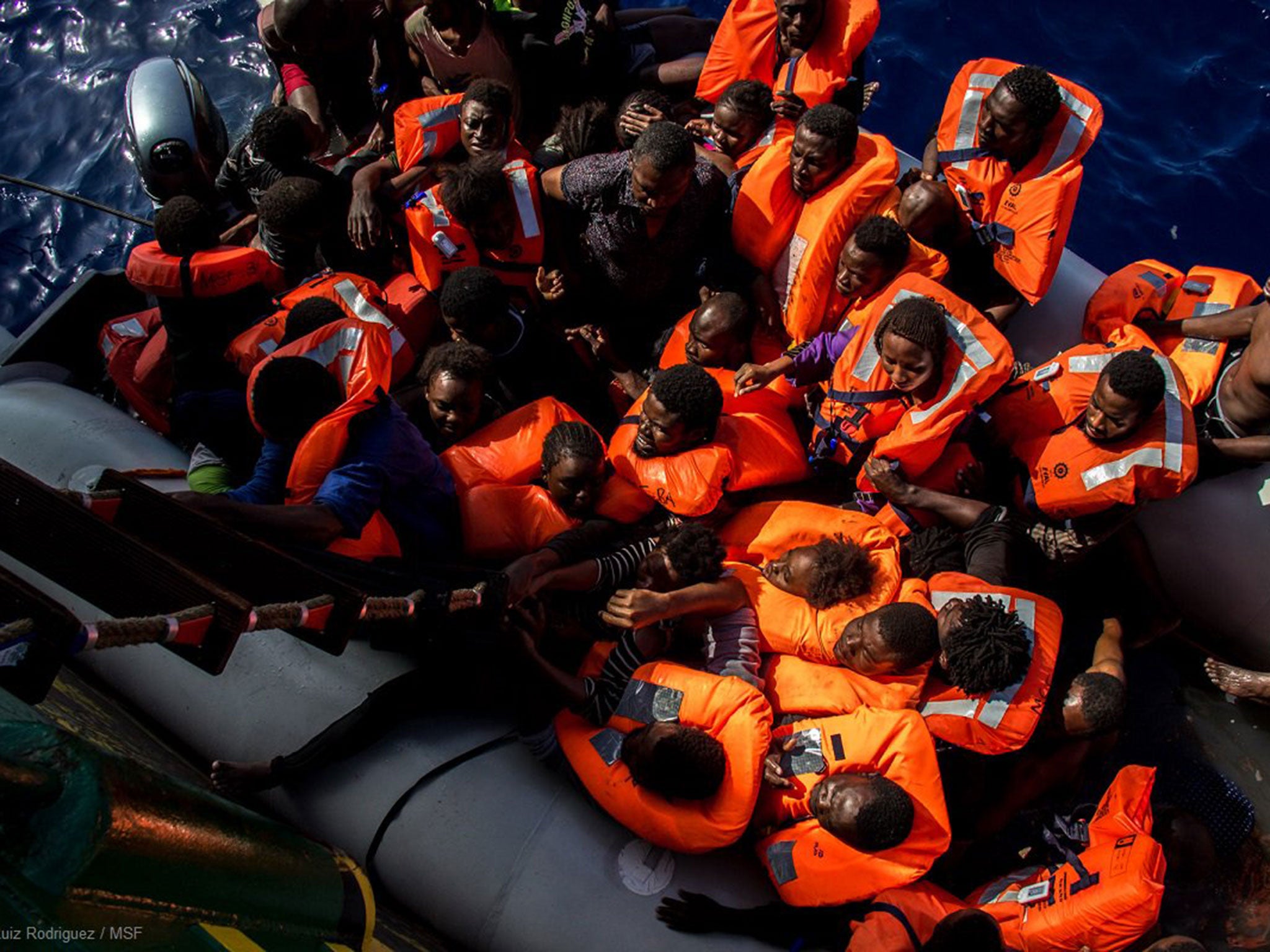 Refugees being rescued from a rubber dinghy where 25 bodies were found off the coast of Libya on 25 October
