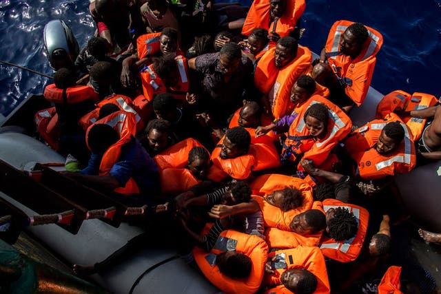 Refugees being rescued from a rubber dinghy where 25 bodies were found off the coast of Libya on 25 October