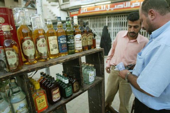 An Iraqi man sell bottles of alcohol at his stall in the centre of Baghdad, 22 June 2003