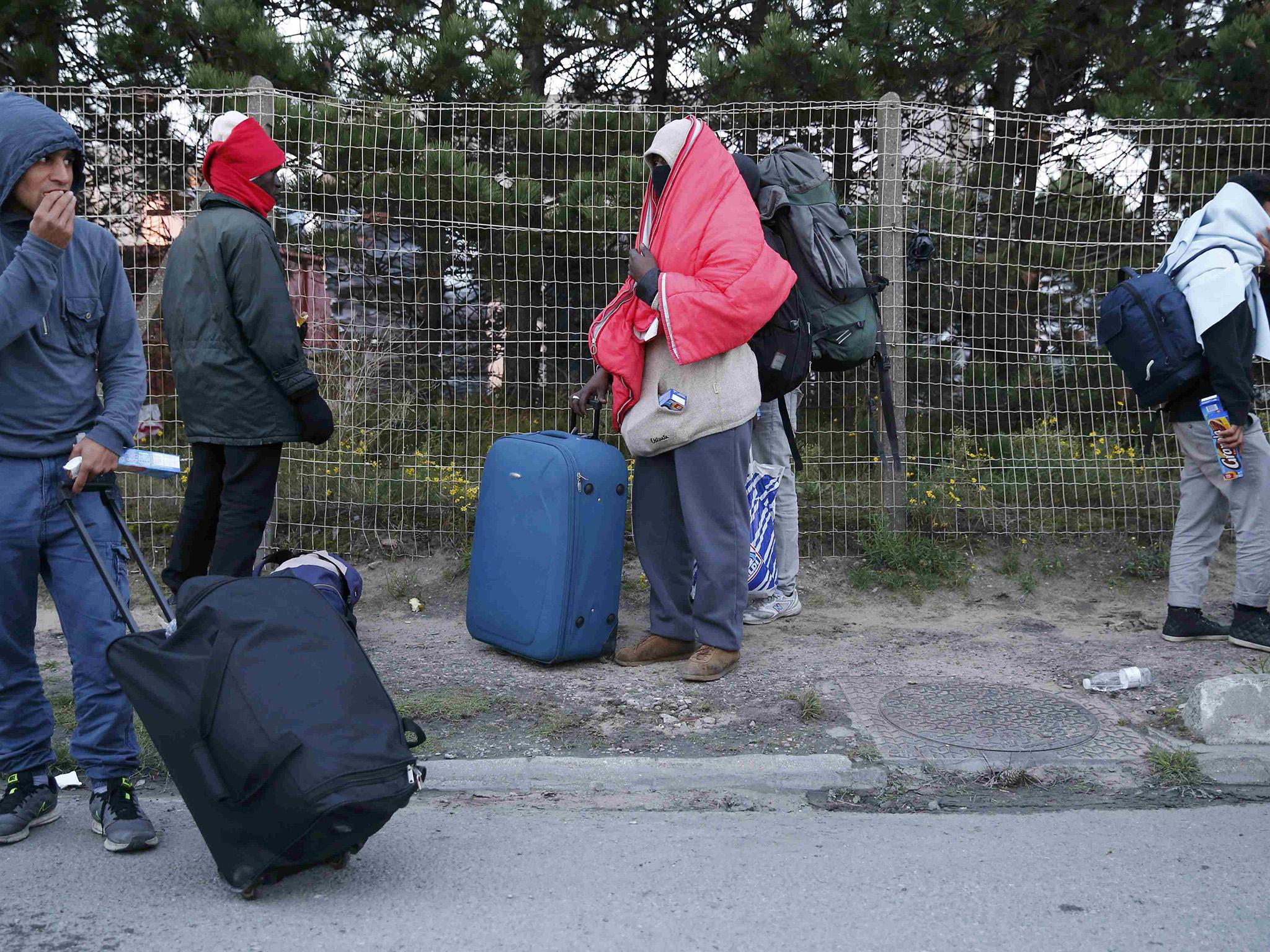 Migrants with their belongs gather on a street and protect themselves from the cold as they prepare to spend the night after the dismantlement of the "Jungle" camp in Calais,