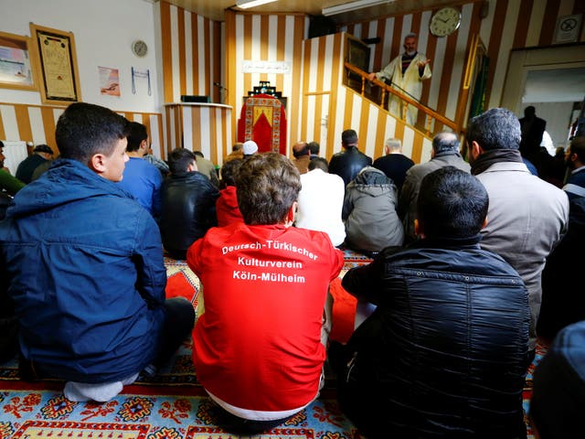 Young Muslims listen to a Turkish imam during Friday prayers at the Turkish Kuba Camii mosque located near a hotel housing refugees in Cologne's district of Kalk