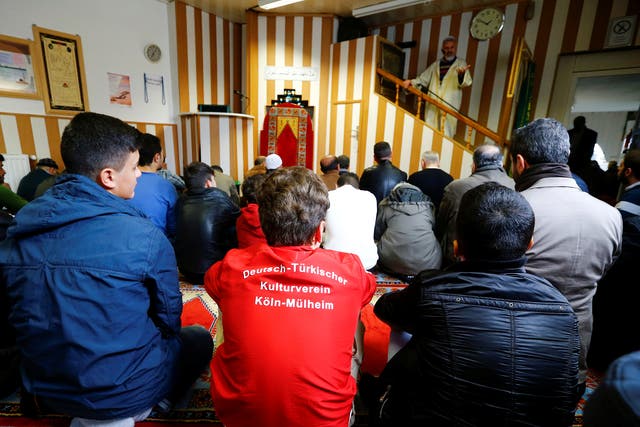 Young Muslims listen to a Turkish imam during Friday prayers at the Turkish Kuba Camii mosque located near a hotel housing refugees in Cologne's district of Kalk