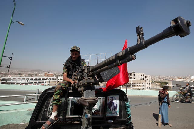A Houthi militant sits atop a police patrol truck stationed on a bridge in the capital Sanaa