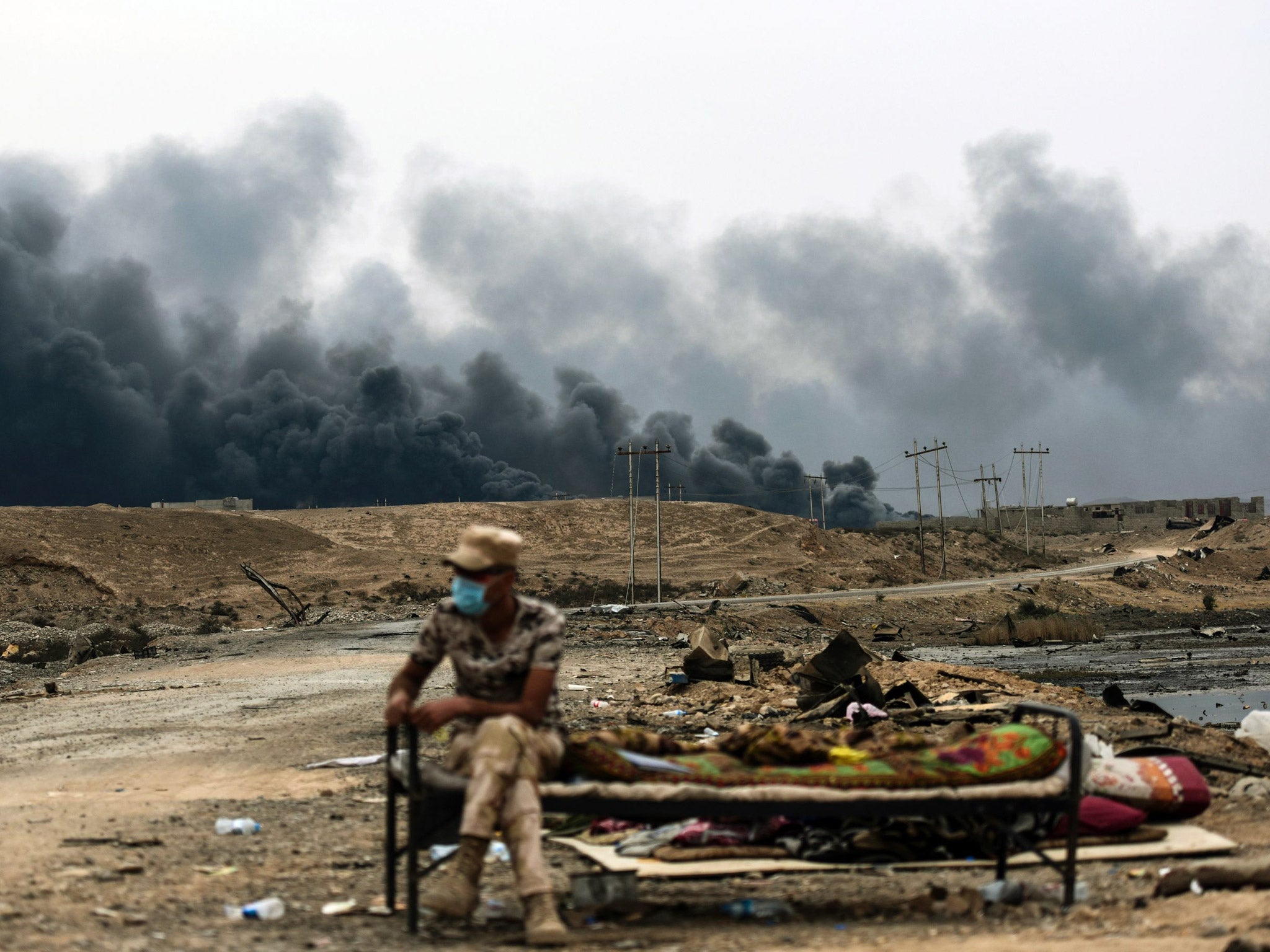 An Iraqi soldier sits at a checkpoint in an area near Qayyarah